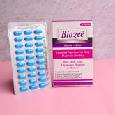 Biozee Biotin + Zinc supplement box and blister pack of blue tablets on pink surface