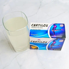 Phlox Cartilox joint supplement sachets with a glass of dissolved drink on a white surface