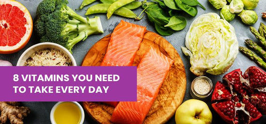 Fresh salmon, leafy greens, and fruits on a table highlighting daily vitamin-rich foods